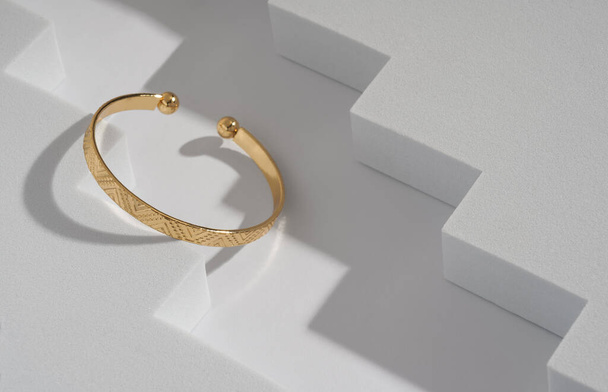 Modern golden bracelet on geometric zigzag white background - Fotó, kép