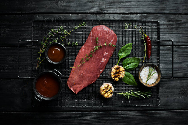 A piece of fresh veal on a slate plate with spices and herbs. Meat. On a stone background. - Fotografie, Obrázek