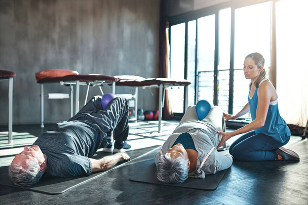 Shot of two seniors working out with a physiotherapist. - Фото, зображення