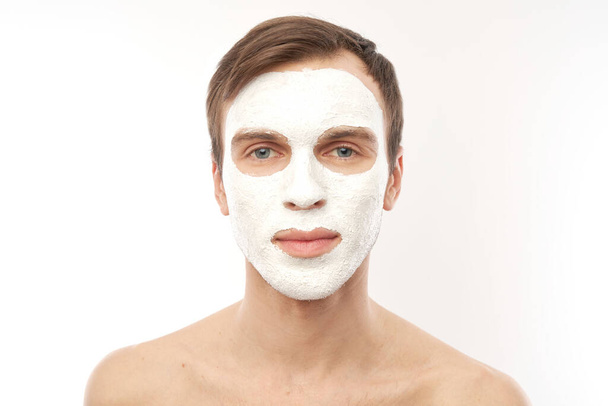 Portrait of young handsome man with cosmetic mask on his face isolated on white background - Valokuva, kuva