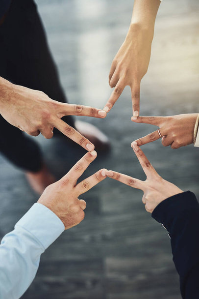 Closeup shot of an unrecognizable group of businesspeople joining their fingers together in an office. - 写真・画像