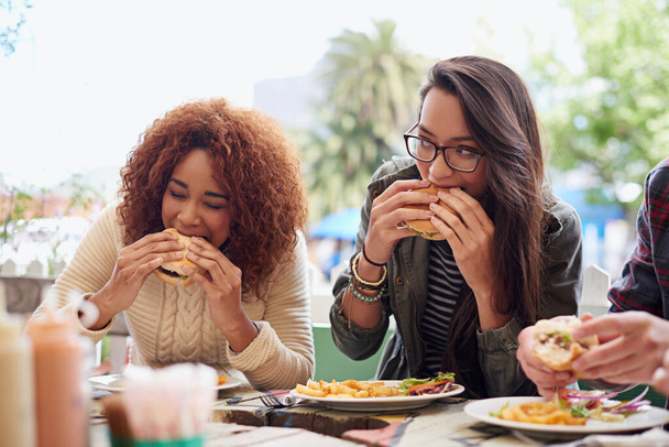 Kasvatettu kuva ystävistä syömässä hampurilaisia ulkona. - Valokuva, kuva