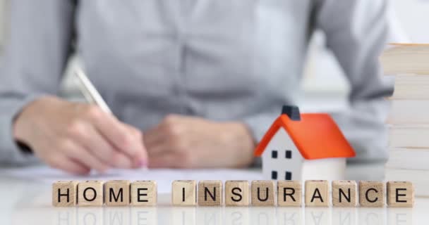 The inscription home insurance on wooden cubes, close-up. Insurance agent making notes, slow motion - Footage, Video