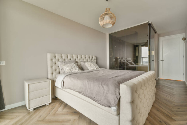 Cómoda cama ubicada cerca de la puerta del balcón con cortinas en el acogedor dormitorio de luz en casa - Foto, Imagen