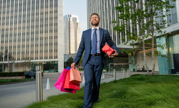 boldog sikeres férfi formalwear bevásárló táska és jelen doboz séta az irodán kívül, nők napja. - Fotó, kép