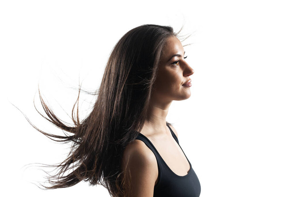 studio portrait of a beautiful brunette girl with flowing hair against white backgroung. - Fotó, kép
