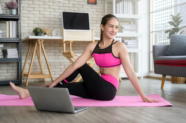 Fit young woman practicing yoga at home via online class with professional instructor, sport and healthy lifestyle concept. - Фото, зображення