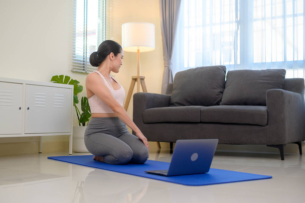 Fit young woman practicing yoga at home via online class with professional instructor, sport and healthy lifestyle concept. - Foto, afbeelding