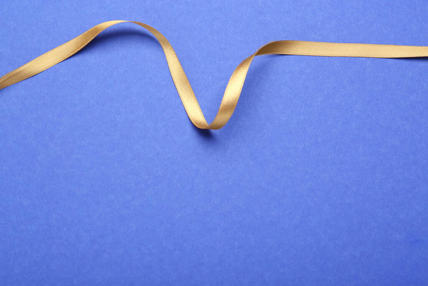 Beautiful golden ribbon on blue background, top view. Space for text - Foto, Imagen