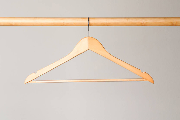 Empty clothes hanger on wooden rail against light grey background - Photo, Image