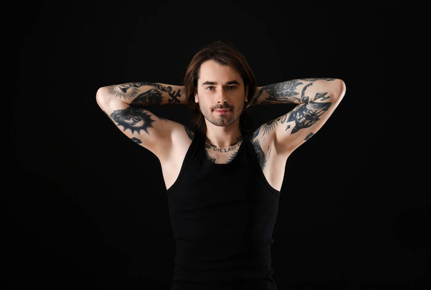 Young man with tattoos on body against black background - Foto, imagen