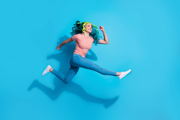 Πλήρες μέγεθος προφίλ πλευρά φωτογραφία της ενεργητικής ενεργό κορίτσι που τρέχει στον αέρα ματιά κενό χώρο που απομονώνονται σε μπλε φόντο χρώμα. - Φωτογραφία, εικόνα