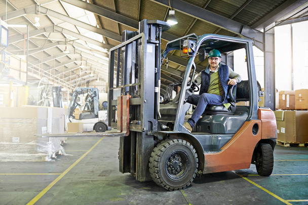 Portrait of driver in a forklift on the factory floor. - Photo, image