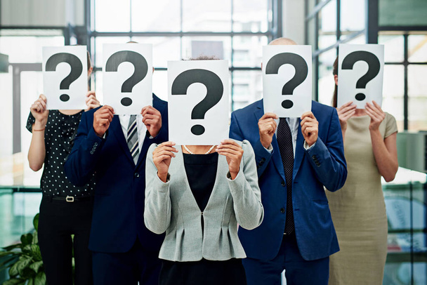 Ujęcie grupy niezidentyfikowanych biznesmenów trzymających tabliczki ze znakami zapytania przed ich twarzami.. - Zdjęcie, obraz