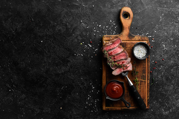 Grilled rib eye steak on a fork, herbs and spices. Top view with copy space for text. Top view with space for copying text - Photo, Image
