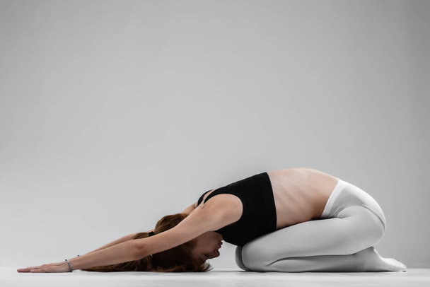 Adatto ballerina ragazza stretching e praticare yoga pose contro sfondo grigio. - Foto, immagini