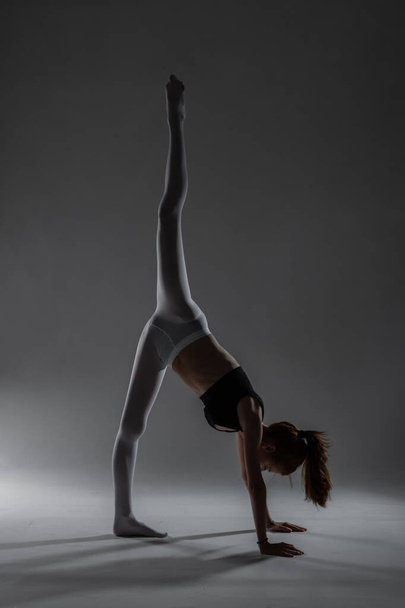 Fit ballerina girl stretching and practicing yoga poses against gray background. - Φωτογραφία, εικόνα