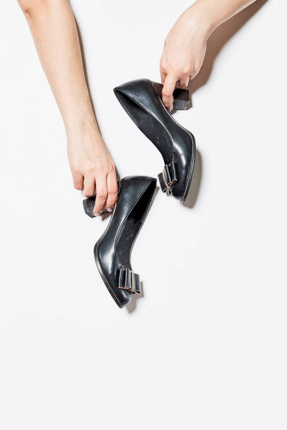 Woman holding black female leather heeled shoes on white backgraund - Foto, afbeelding
