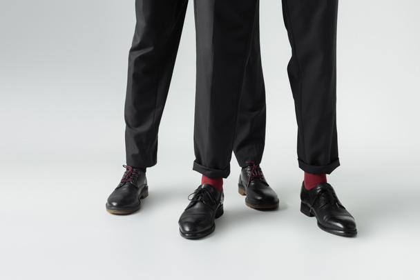 Oříznutý pohled na homosexuální pár v obuvi stojící na šedém pozadí  - Fotografie, Obrázek