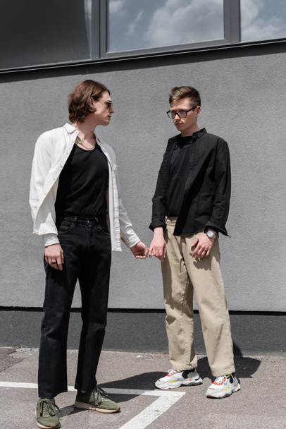 Young same sex couple standing near building on urban street  - Foto, Bild