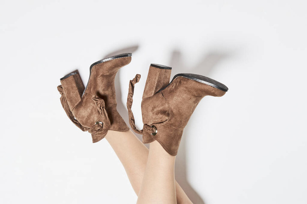 Женские ноги в осенних бежевых замшевых сапогах Стильные женские туфли из натуральных материалов на белом фоне - Фото, изображение