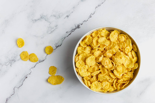 Corn flakes in white bowl on marble table. Top view of healthy breakfast. - Foto, Bild
