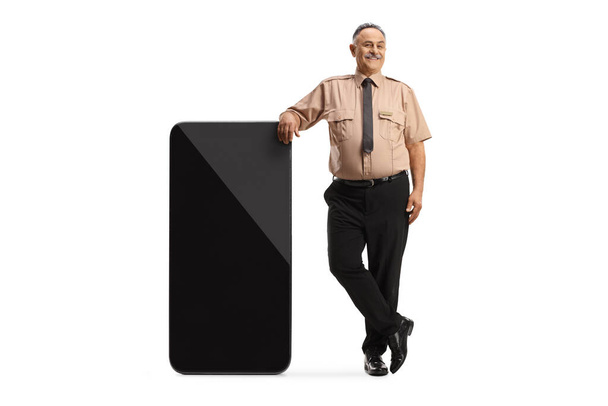 Security officer leaning on a big mobile phone and pointing isolated on white background - Photo, image
