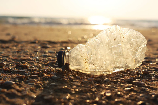 Plastic bottle thrown on the beach . Concept of environmental pollution and damage to nature and animals - Foto, afbeelding