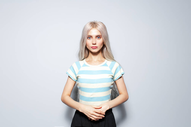 Porträt eines selbstbewussten netten blonden Mädchens in gestreiftem Hemd auf weißem Hintergrund. - Foto, Bild