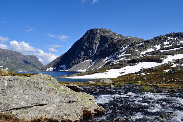 ノルウェーのロムダル地方のDalsnibba丘の下に氷の湖がある雪の山 - 写真・画像