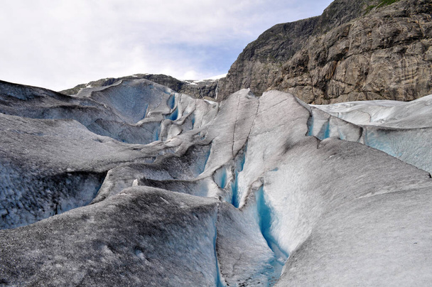 L'enorme ghiacciaio di Jostedalsbreen in mezzo alle montagne rocciose sopra un lago in Norvegia - Foto, immagini