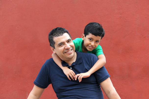 Der alleinerziehende Vater und der dunkelhaarige Latino-Sohn spielen und haben Spaß zusammen und verbringen am Vatertag viel Zeit mit der Familie und feiern den Sieg mit Umarmungen und Küssen - Foto, Bild
