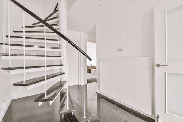 Spiralne schody z szafą i białymi ścianami i drzwiami prowadzą do innego pokoju - Zdjęcie, obraz