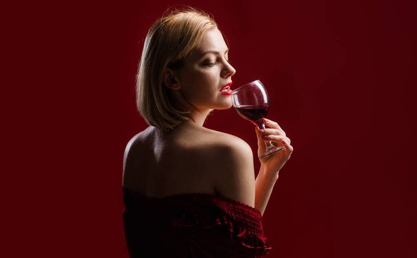 Seksikäs tyttö juo punaviiniä. Nainen viinilasin kanssa. Tyylikäs malli punaisessa mekossa alkoholijuomalla - Valokuva, kuva