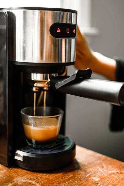 An espresso coffee coming out from an automated coffee maker machine - Photo, image