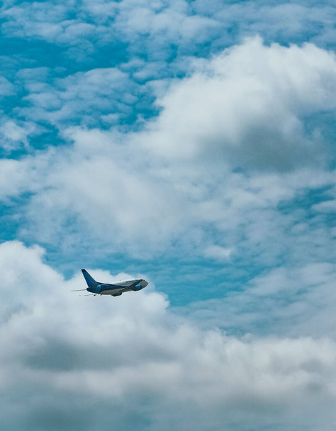 A vertical shot of the airplane flying against the cloudy blue sky. - Foto, Bild