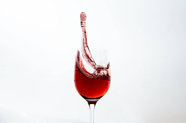 A view of wine glass with splashing wine isolated in white background - Photo, image