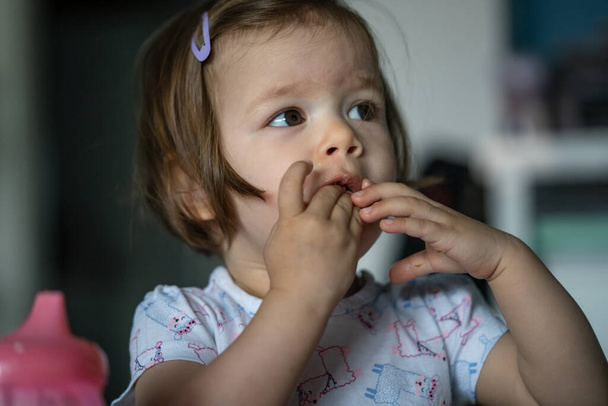 Одна девочка маленький кавказский ребенок сидит за столом дома один едят завтрак или обед выпечки с йогуртом в одиночку в день реальные люди растут концепция развития скопировать пространство - Фото, изображение