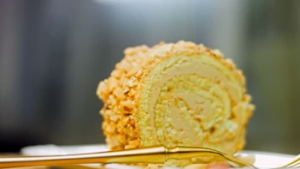 Gâteau aux cacahuètes sur une assiette avec une fourchette en or. En arrière-plan se trouvent des cacahuètes pelées sur un plateau de cuisson de style rétro. Macro et curseur de tir. - Séquence, vidéo