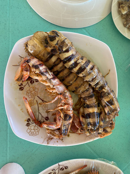 Foto di un gamberetto mantide, locusta marina, assassino di gamberetti o splitter pollice, un crostaceo marino carnivoro dell'ordine Stomatopoda servito su un piatto una delicatezza di pesce filippino. - Foto, immagini