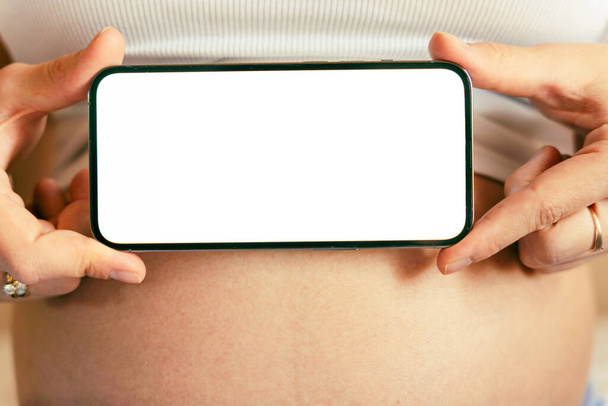 Pregnancy mockup display. Pregnant woman holding smartphone. Mobile pregnancy online maternity application mock up. Concept maternity, pregnancy, childbirth - Photo, Image
