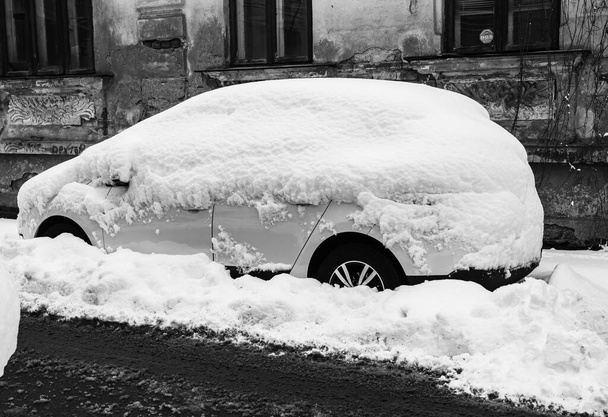 Havas autó hóval borítva egy parkolóban. Bukarest, Románia, 2020. - Fotó, kép