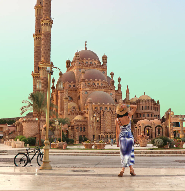 エジプトの旧市街にあるエル・ムスタファ・モスクを背景にした少女。エジプトの概念への旅行。シャルム・エル・シェイクの観光都市の古代のモスク。高品質の写真 - 写真・画像