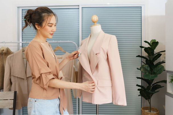 Концепция дизайна моды, азиатская женщина портной проверяет качество полноты костюма на манекене. - Фото, изображение