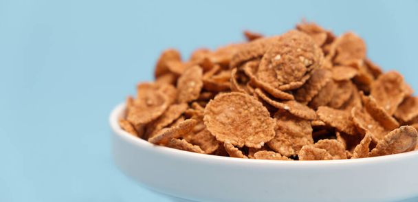 Durum wheat flakes - quick breakfast cereal on a plate on a light blue background - Photo, Image