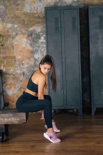 Sporty woman in sportswear resting on bench at fitness. Healthy people relax after workout. Sport and gym concept - Photo, Image
