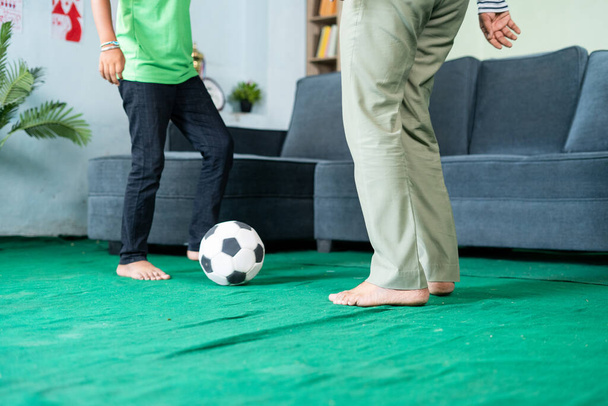 zbliżenie strzał ojca i syna grających w piłkę nożną w domu przez kopanie - koncepcja spędzania wolnego czasu, rodziny i ćwiczenia gry. - Zdjęcie, obraz