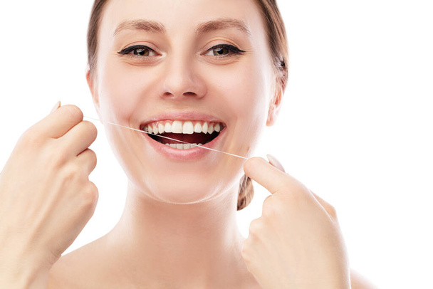 Smiling woman using tooth floss cleaning and caring for perfect teeth posing on isolated white  background. Teeth Flossing. - 写真・画像