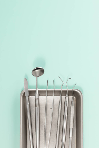 A set of dental metal instruments for treating and checking teeth. Top view on blue background - Valokuva, kuva