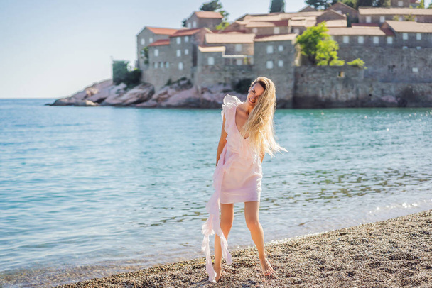 Woman tourist on background of beautiful view of the island of St. Stephen, Sveti Stefan on the Budva Riviera, Budva, Montenegro. Travel to Montenegro concept. - Fotó, kép